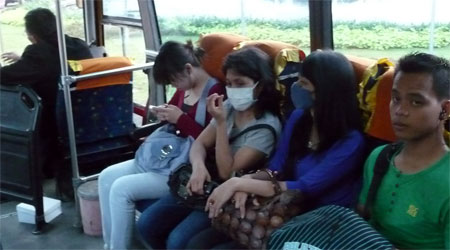 dua penumpang transjakarta menggunakan masker