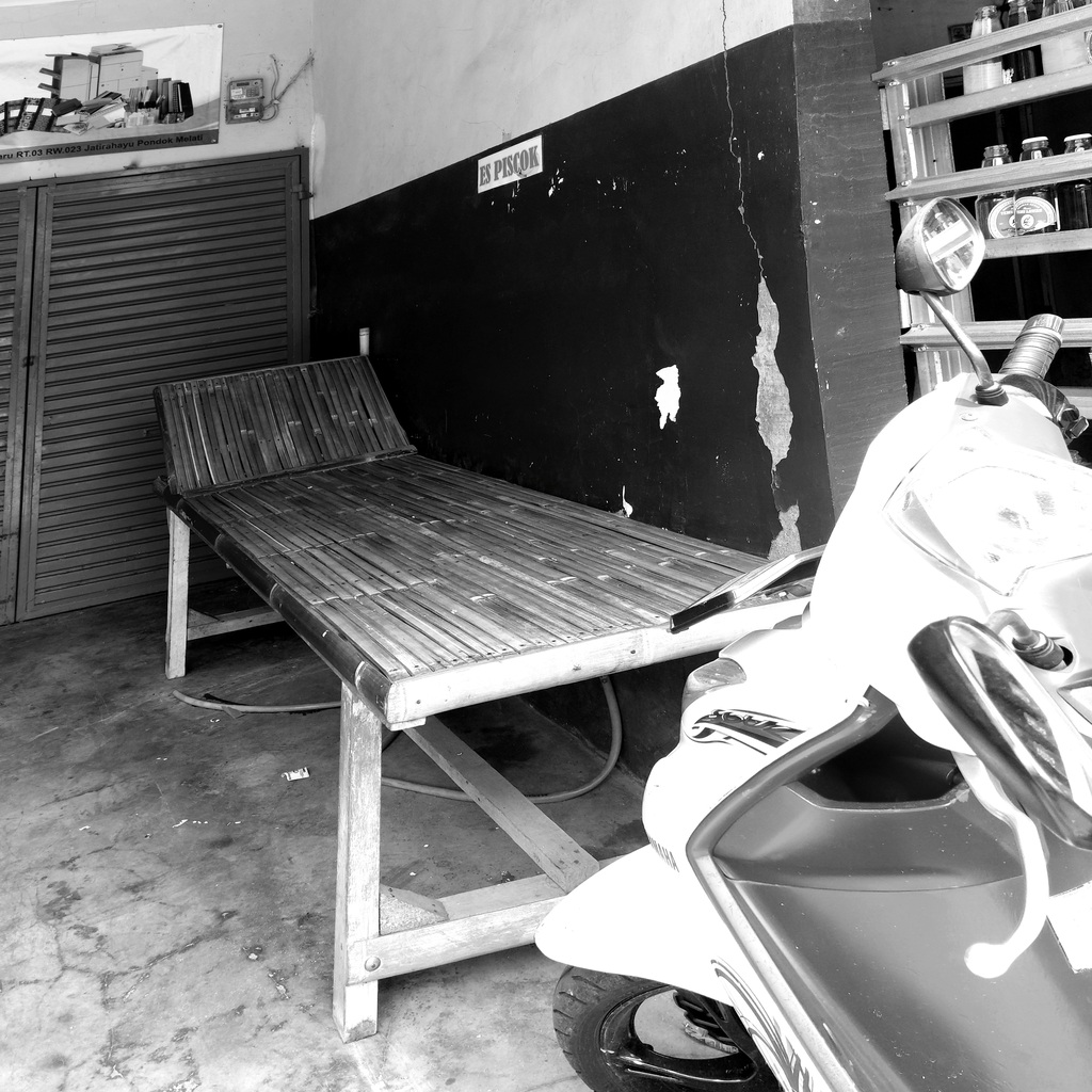 Balai-balai bambu model kursi malas di teras rumah petak kontrakan 